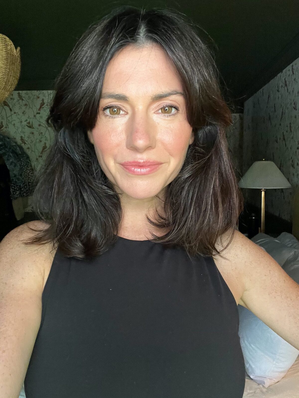 Woman is standing in her bedroom wearing a black top after doing a 10-minute makeup routine