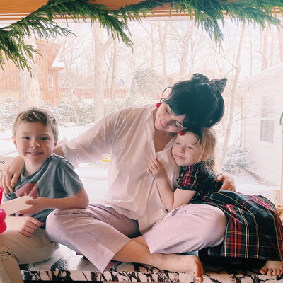 Woman sitting next to her children  hugging them