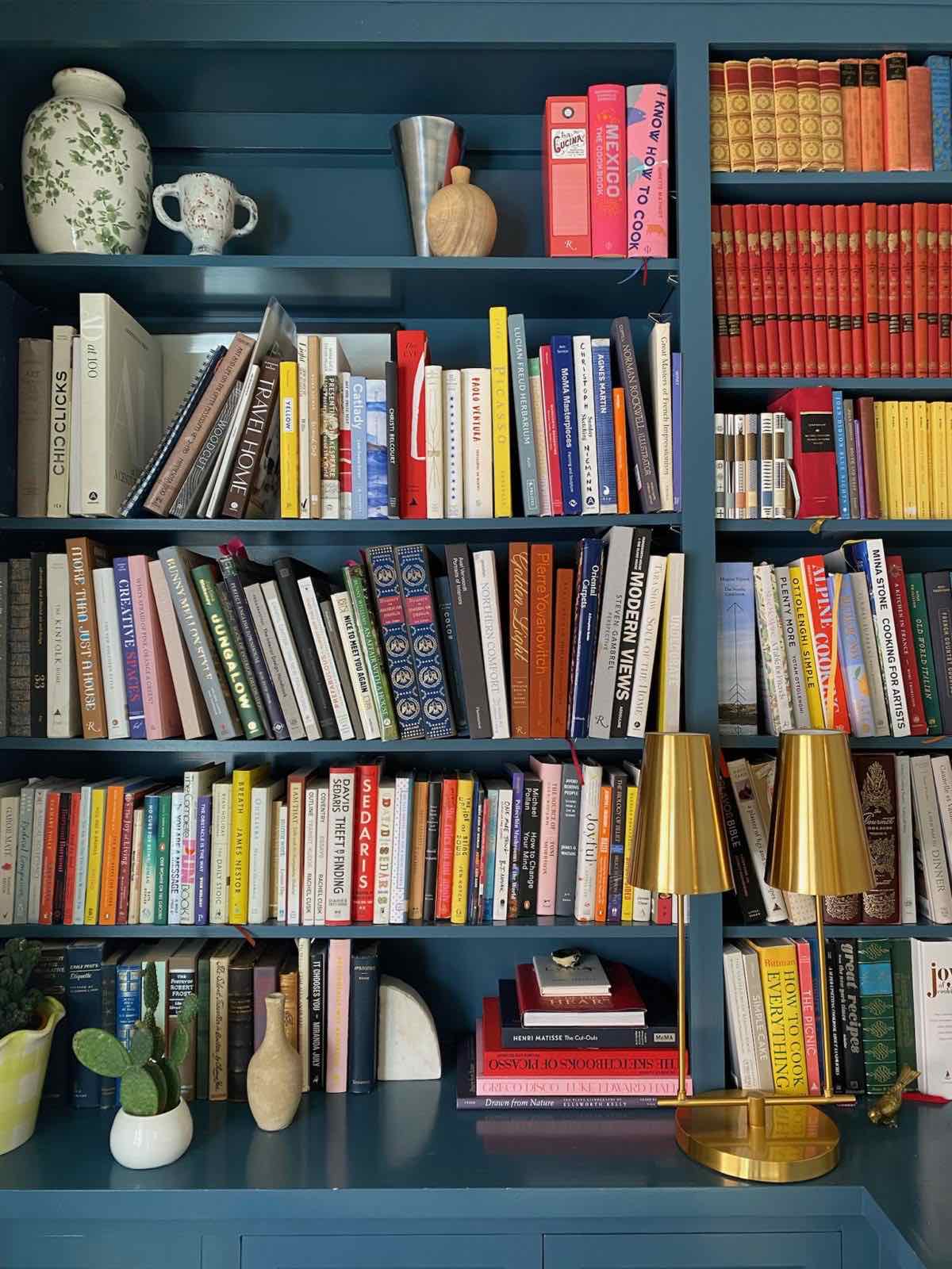 Colorful design books on a blue-painted bookshelf