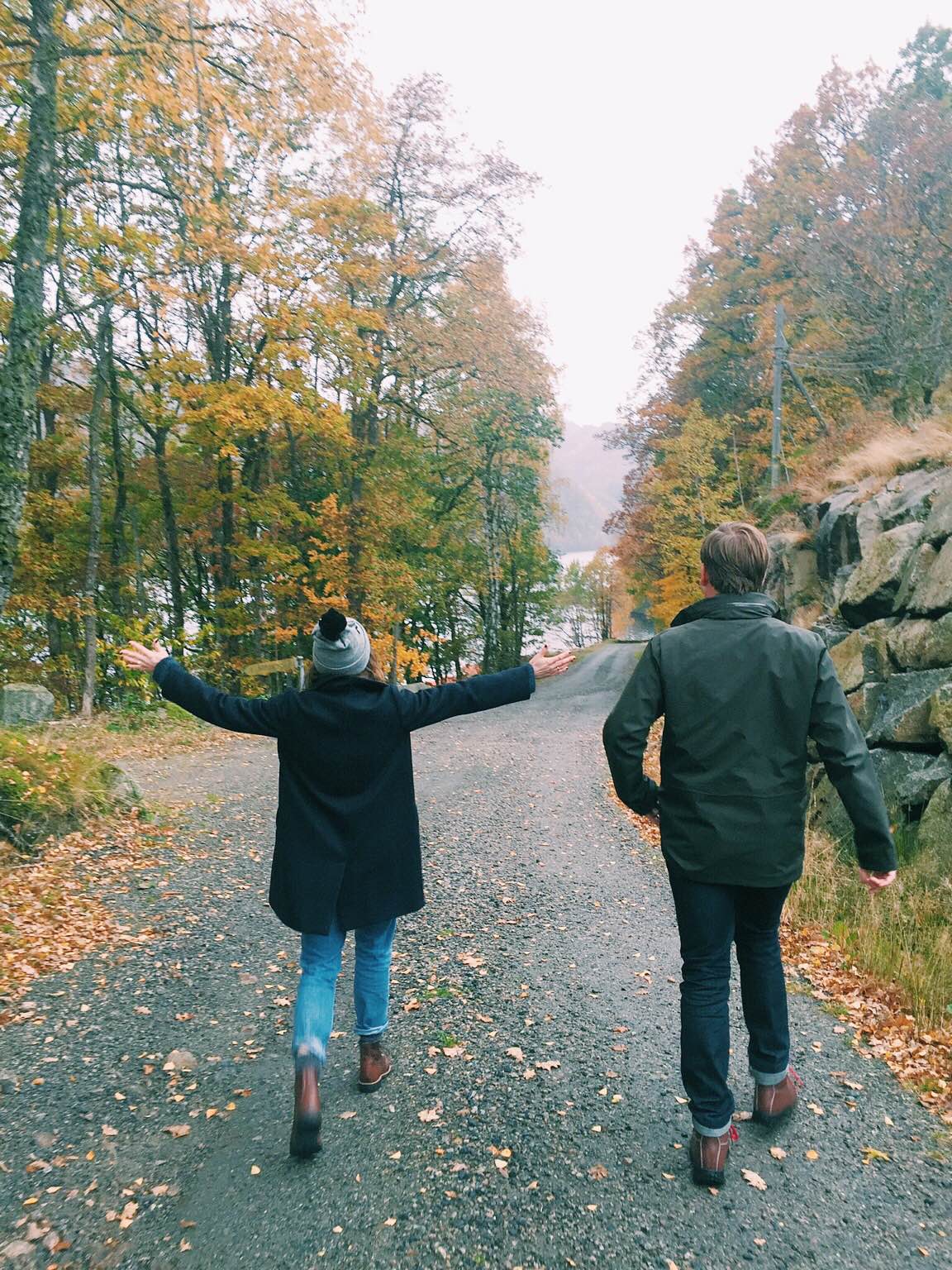 couple walking down a path lined with trees in the fall