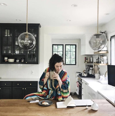 Woman sitting down at a  table drinking coffee and  reading the newspaper