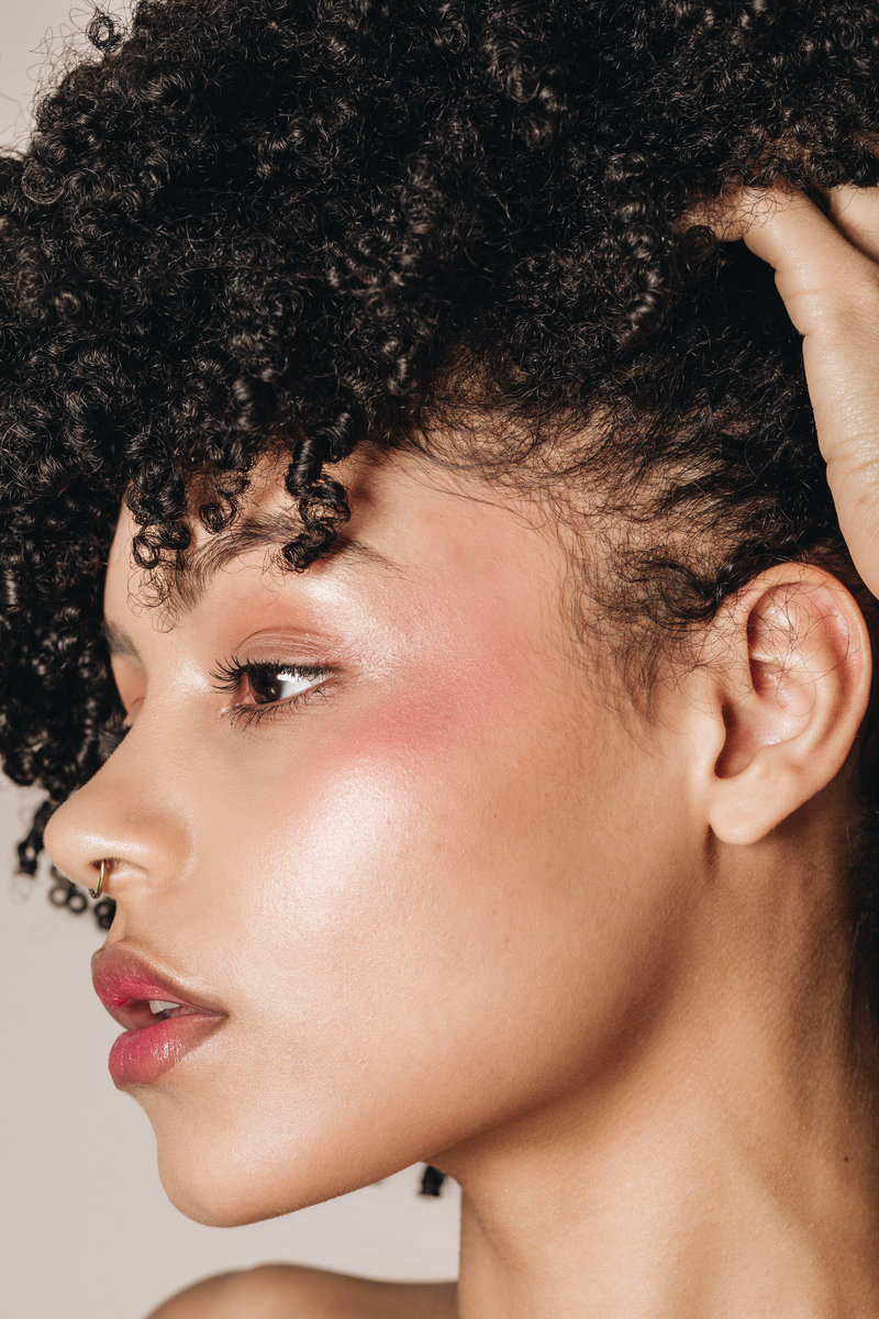 woman pulling back her hair to show her eye makeup