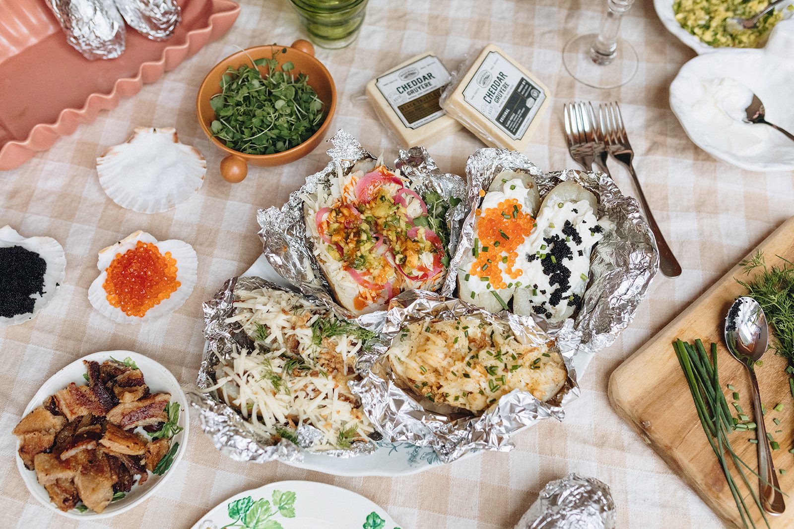 A plate of baked potatoes with a variety of toppings are displayed on top of a table. 