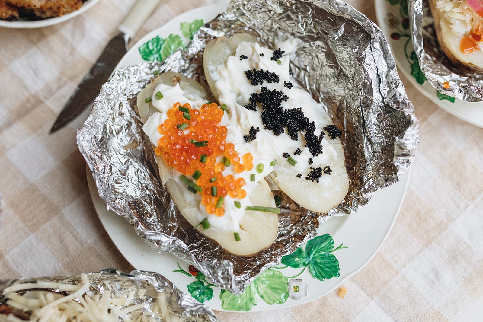 A baked potato covered with Black Truffle Cheddar Gruyere, Sour Cream, Caviar, and Chives